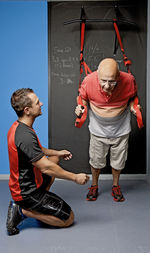 Personal trainer helping client with suspension training in gym