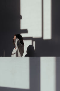 Side view of woman standing against window