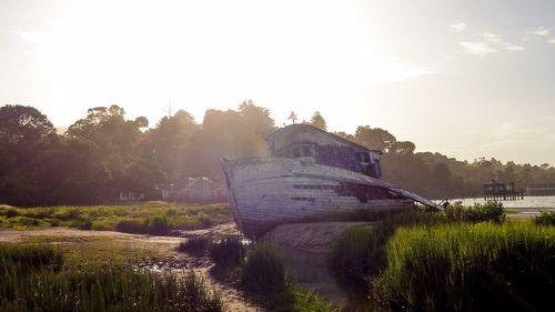 Abandoned boat moored on shore against sky