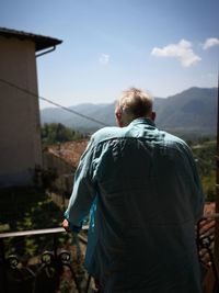 Rear view of man standing on balcony