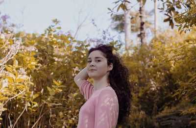 Close-up of young woman standing against tree