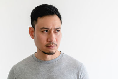 Portrait of young man standing against white background