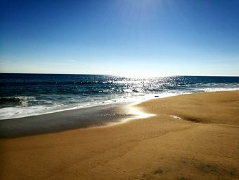 Scenic view of beach against clear blue sky