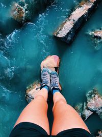 Low section of woman standing on rock in stream