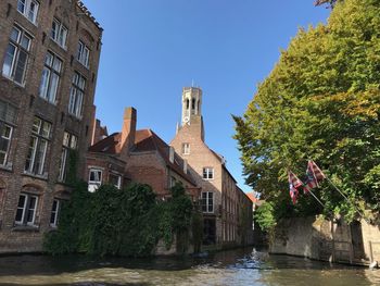 Buildings by river against clear sky