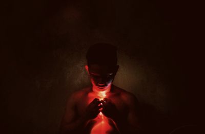 Hand holding red light against black background