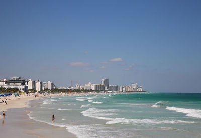 People at beach against blue sky during sunny day