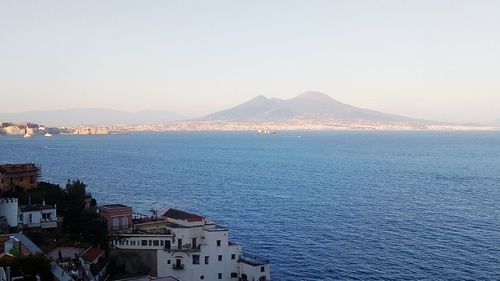 Scenic view of sea by town against clear sky