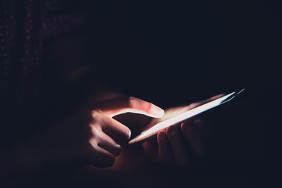 Close-up of person using smart phone over black background