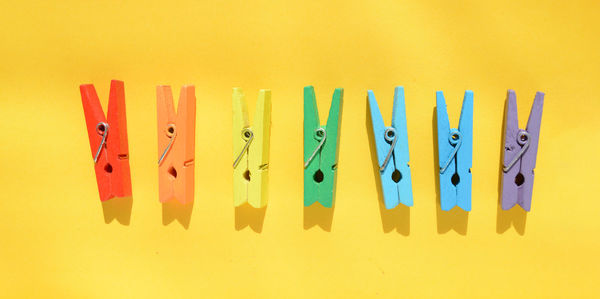 Close-up of multi colored pencils in row against yellow background