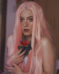 Portrait of young woman holding red rose at home