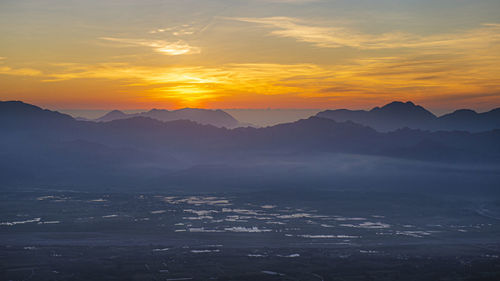 Scenic view of silhouette mountains against orange sky