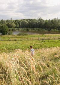 Scenic view with boy in agricultural field against sky