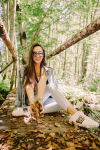 Portrait of smiling woman sitting in forest