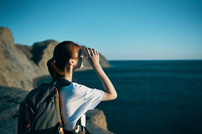 Woman photographing sea against clear sky