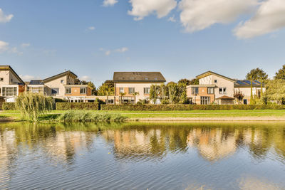 Houses by lake against sky