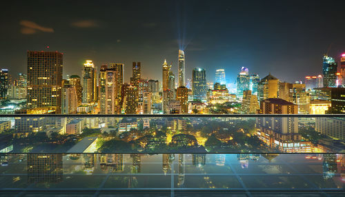 Illuminated buildings in city against sky at night