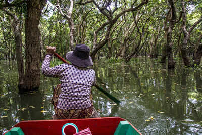 Rear view of woman standing by tree in forest