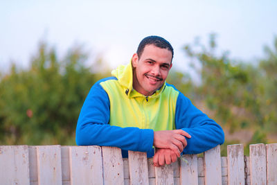 Portrait of smiling man against wooden fence