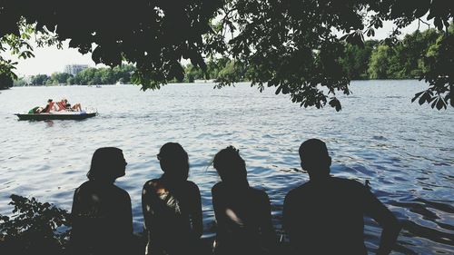 Rear view of silhouette people on boat against trees