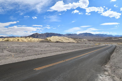 Road leading towards mountains against sky