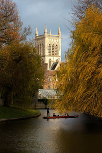 People on building by canal against sky