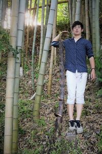 Portrait of teenage girl standing by tree trunk in forest