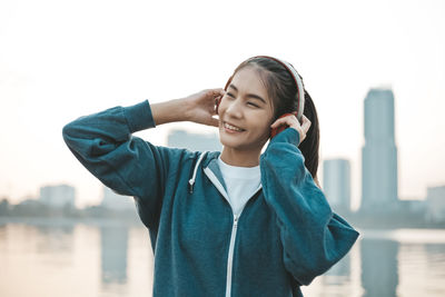 Portrait of smiling young woman standing against clear sky