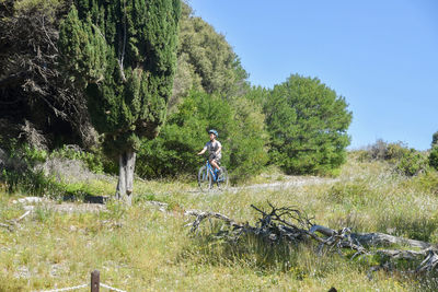 Boy riding bicycle on road against trees