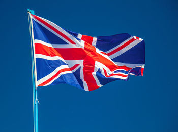 Low angle view of american flag against clear blue sky