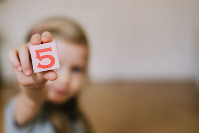 Girl holding toy block while playing at home