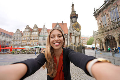 Self portrait of young woman in bremen market square with roland statue, germany