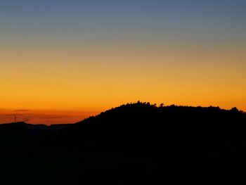 Scenic view of silhouette mountains against orange sky