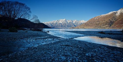Scenic view of lake and mountains against clear blue sky