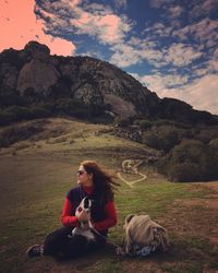 Young woman looking away sitting with dog on field