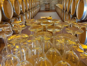 Upside down wineglasses on table against barrels in cellar