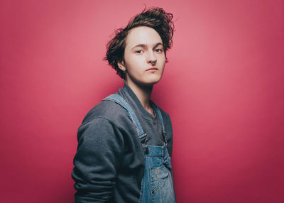 Portrait of confident male hipster standing against pink background