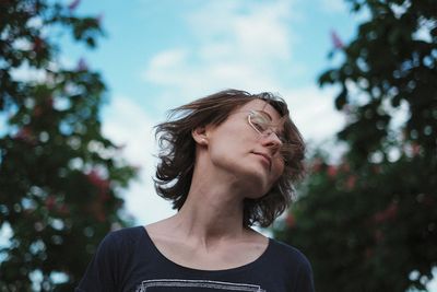 Woman tossing hair while standing against sky