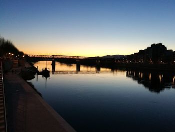 Silhouette of bridge over river during sunset