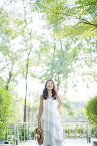 Woman standing by tree against plants