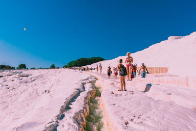 People on beach against clear blue sky