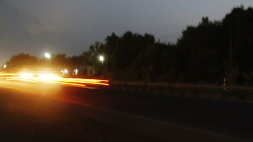 Cars on illuminated street against sky at night