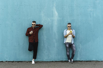 Portrait of a young couple standing against wall