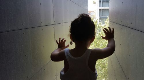 Rear view of woman standing against wall