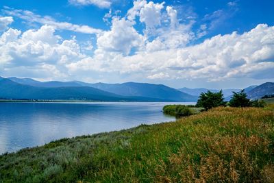 Scenic view of lake by field against sky