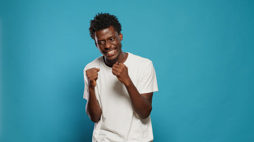 Young man standing against blue background