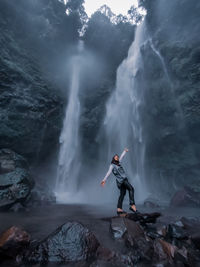 Women standing on rock against waterfall