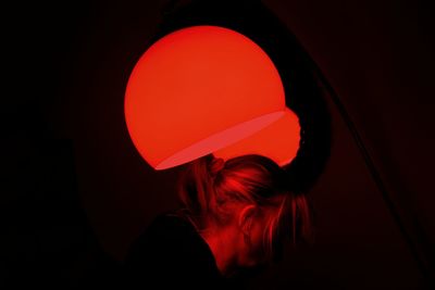 Rear view of woman with red light against black background