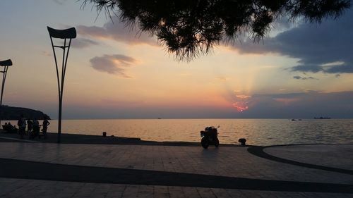 Silhouette people by sea against sky during sunset