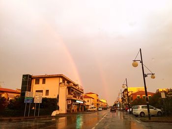 Rainbow over road in city against sky